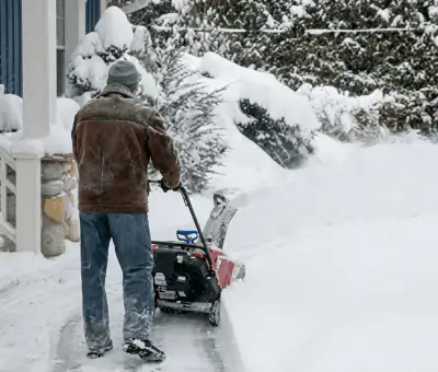 Residential snow removal technician using a snow blower to clear a home driveway and walkway in Jackson, MS